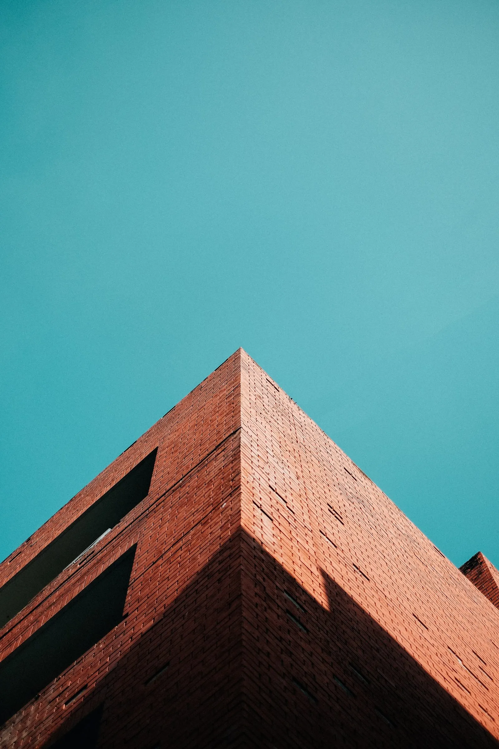 Corner of a red brick building rising into a clear sky