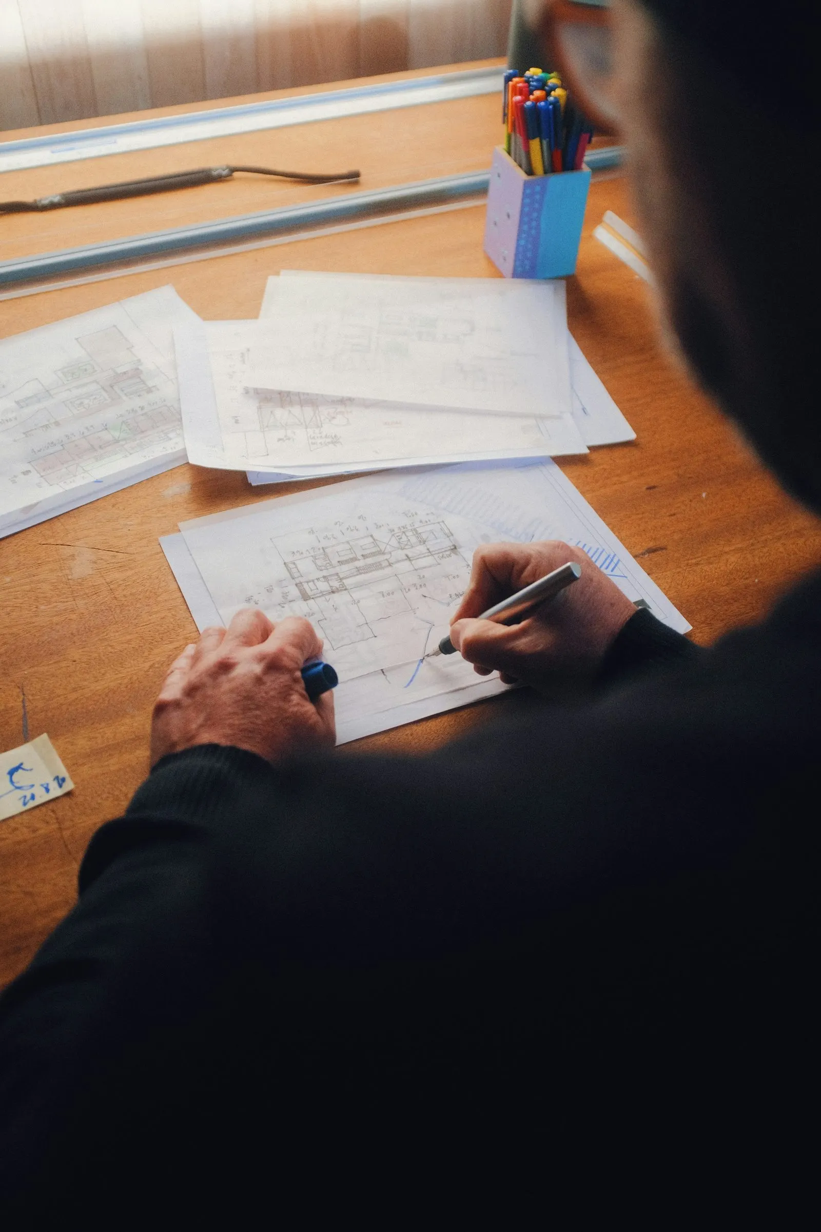 Hands marking up architectural plans on a desk